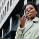 Femme qui passe un appel téléphonique en extérieur avec son smartphone, avant de composer un numéro surtaxé en 0820