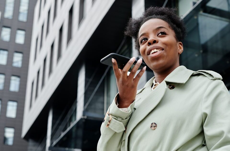 Femme qui passe un appel téléphonique en extérieur avec son smartphone, avant de composer un numéro surtaxé en 0820