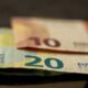 Billets de 10 et 20 euros posés sur un smartphone, illustrant le coût d'un appel vers le numéro 0899 le plus cher