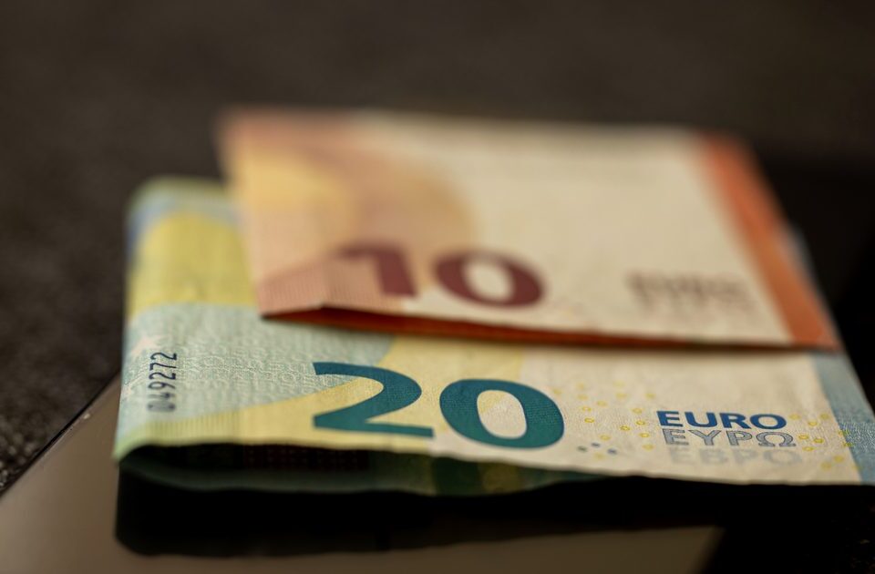 Billets de 10 et 20 euros posés sur un smartphone, illustrant le coût d'un appel vers le numéro 0899 le plus cher