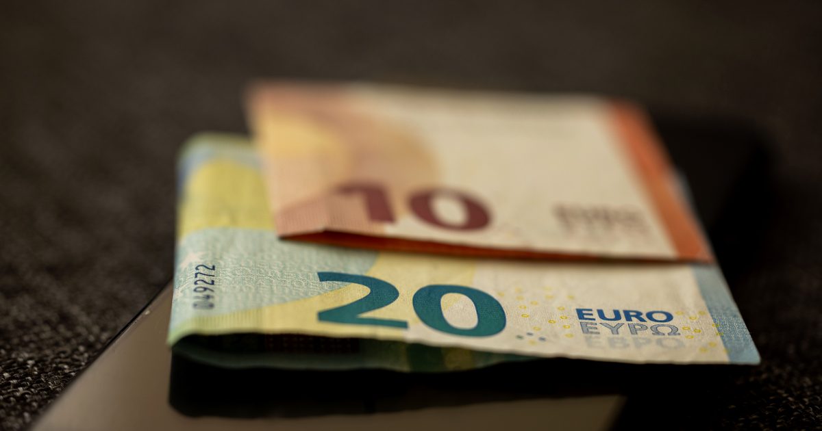 Billets de 10 et 20 euros posés sur un smartphone, illustrant le coût d'un appel vers le numéro 0899 le plus cher